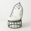 Leaf-shaped dark green outdoor woven accent chair with plush white cushions